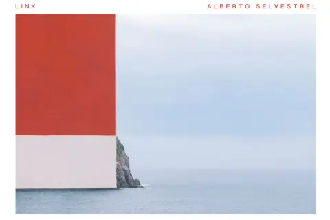 Scogliera rocciosa con mare calmo e cielo azzurro, con un blocco rosso e bianco che incombe a sinistra. Opera di Alberto Selvestrel.