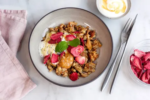 En skål med granola, yoghurt, jordnötssmör, torkade jordgubbar och mynta. En perfekt nyttig frukost för en bra start på dagen.