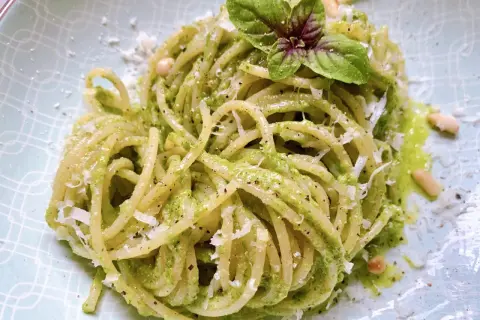 Ein Teller mit köstlichen Pesto Nudeln, garniert mit frischem Basilikum und Pinienkernen.