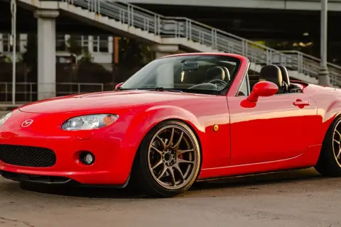 Mazda MX-5 rouge rutilante, parfaite pour un jeune permis rêvant de sa première voiture sport.