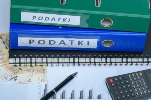 Segregator z napisem "PODATKI", pieniądze, kalkulator i wykres. Szukasz sposobu, jak zmniejszyć podatek za budynki gospodarcze?