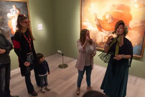 Un grupo de personas, incluyendo una niña, disfruta de una visita guiada en el **Día de los Museos Zaragoza**, admirando obras de arte.