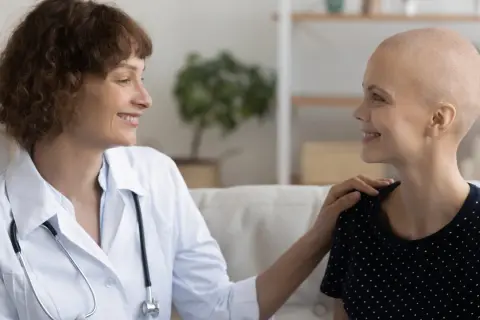 Ärztin tröstet Patientin, die ihre Haare wegen Chemotherapie verloren hat. Hoffnungsvolles Gespräch über die Chemotherapie Dauer.