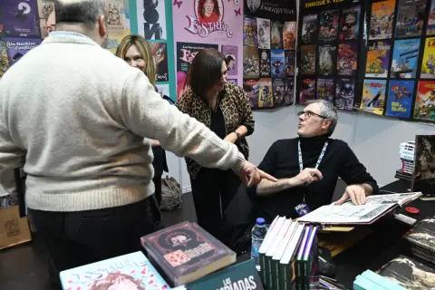 En la Comic Con Zaragoza, un autor firma cómics mientras fans observan.