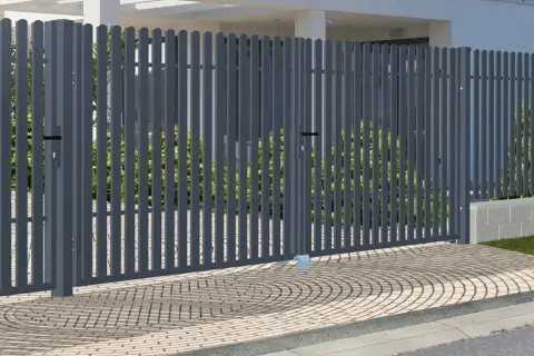 Nowoczesna, szara brama do ogrodzenia panelowego, z dwoma skrzydłami, otwiera drogę do zadbanego ogrodu.