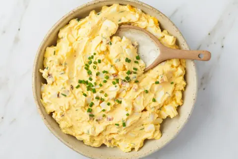 Kremowa pasta jajeczna z jogurtem, posypana szczypiorkiem, w ceramicznej misce. Idealna na kanapki.