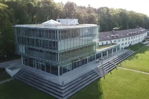 Moderner Glasbau der Hochschule Friedrichshafen mit angrenzendem Campus und Wald.