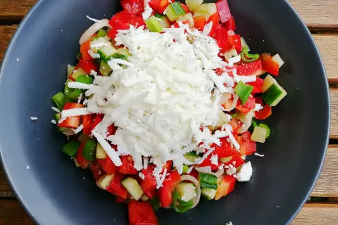 En fräsch sopska salata med hackad tomat, gurka, paprika och lök, toppad med riven ost.