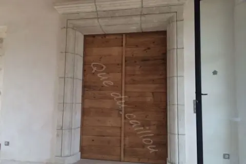 Un encadrement de porte en pierre, avec une couleur différente de la porte en bois brut.