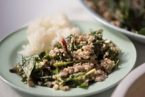 En tallrik med ris och en kryddig kötträtt med färska örter och chili. En smak av äkta thai kryddor.