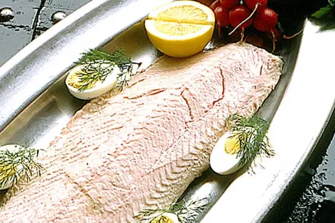 En vacker inkokt lax på ett silverfat, garnerad med ägg, citron och dill. Perfekt för en svensk sommarmåltid.