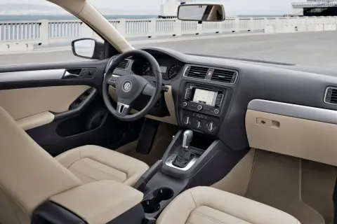 Wnętrze VW Jetta MK6 z jasną tapicerką, nawigacją i automatyczną skrzynią biegów.