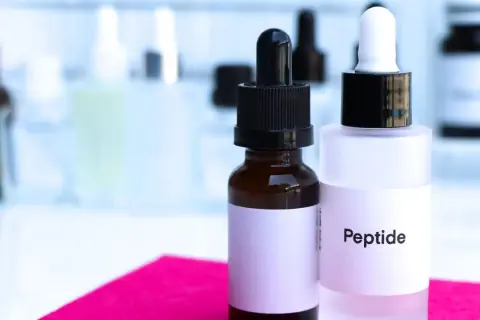 Dwie buteleczki z pipetkami, jedna z napisem "Peptide", sugerują zawartość peptydów miedziowych, kluczowych składników w pielęgnacji skóry.