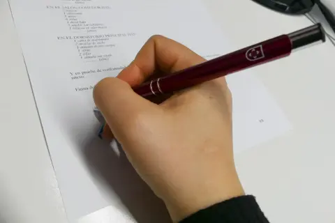 Mano con bolígrafo revisando un inventario de muebles para un contrato de alquiler, cumpliendo la ley de arrendamientos urbanos.