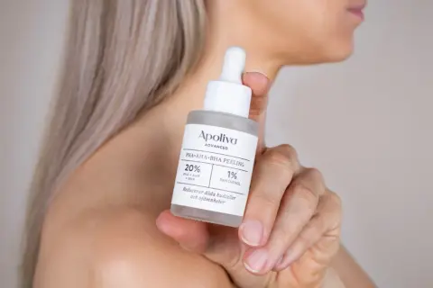En hand håller en flaska med Apoliva PHA+AHA+BHA PEELING. Denna aha syra-produkt hjälper till att reducera döda hudceller.