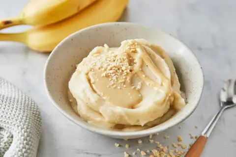 Cremiges italienisches Bananeneis mit Karamellsauce und gehackten Nüssen, garniert mit frischen Bananen.