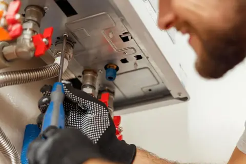 Tecnico con guanti lavora su caldaia Baxi in blocco, cercando di sbloccarla con un cacciavite.