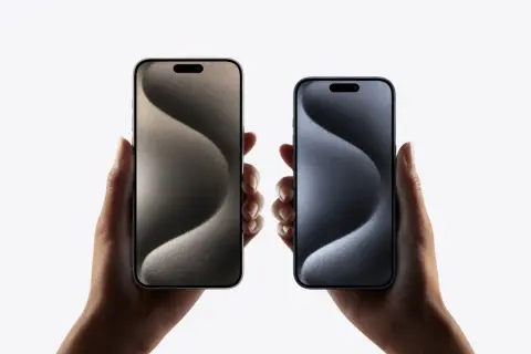 Dwie dłonie trzymają iPhone'y 15 w różnych kolorach. Zastanawiasz się nad ich **pojemnością baterii**?