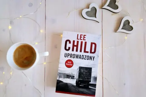Książka "Uproszczony" Lee Child, filiżanka kawy i ozdobne serca na białym tle.