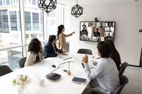 Ein Team im Büro nimmt an einer Videokonferenz teil, was zeigt, was ist hybrides arbeiten: Präsenz und Remote-Teilnehmer vereint.