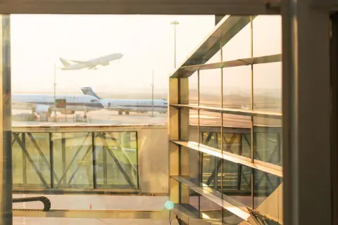 Flugzeuge starten und landen am Flughafen. Ein Flugzeug hebt ab, während andere am Gate warten. Gut, dass ich weiß, wie viel eher am Flughafen sein muss.