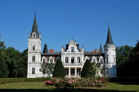 Imponujący pałac w Posadowie z wieżami i ozdobnym ogrodem.