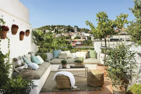 Un rincón perfecto para **chill out** en la **terraza**, con cómodos cojines, plantas y vistas a la ciudad.