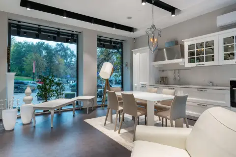 Espaciosa cocina salón comedor de 30 m2 con isla, mesa y sillas, sofá blanco y gran ventanal.
