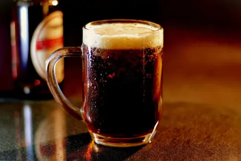 Chłodny, ciemny lager z gęstą pianką w szklanym kuflu, obok butelki.