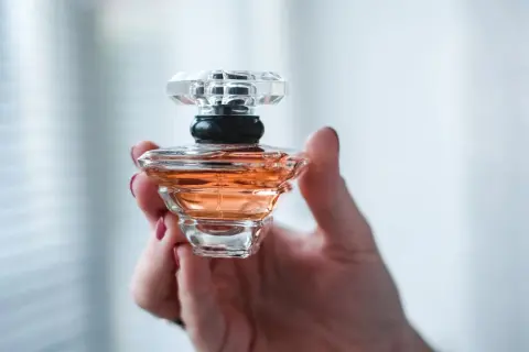 Dłoń trzyma flakonik perfum o bursztynowym kolorze. Wygląda jak dzieło sztuki, może to baccarat kurkdjian?