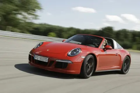 Czerwony Porsche 911 GTS Targa pędzi po torze wyścigowym, kierowca cieszy się jazdą.