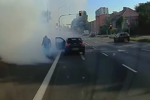 Rozbiegany diesel dymi na skrzyżowaniu. Kierowca wysiada z auta, otaczając go biała chmura.
