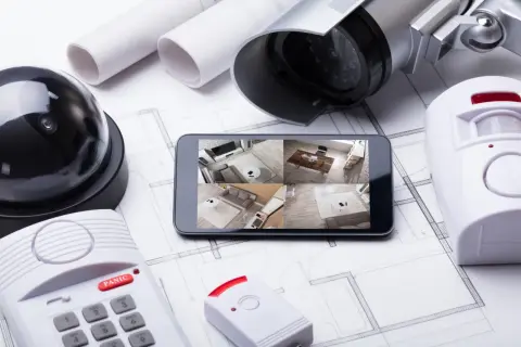 Kit d'alarme à installer soi même : caméra, détecteur de mouvement, centrale et smartphone affichant les flux vidéo.