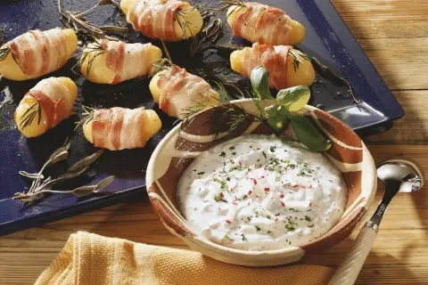 Leckere Kartoffeln im Speckmantel mit Kräutern und einem Dip.