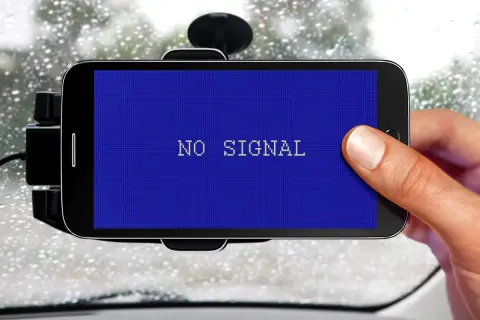Smartfon w uchwycie samochodowym pokazuje komunikat "NO SIGNAL". Problem z GPS w deszczowy dzień.