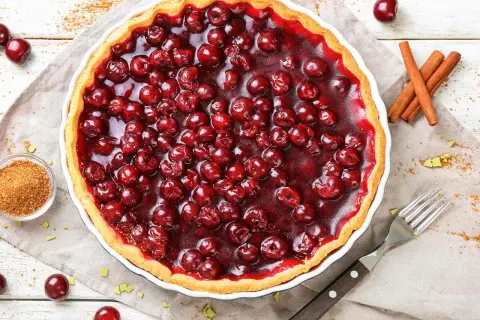 Une délicieuse tarte aux cerises, garnie de fruits rouges brillants et d'une croûte dorée. Parfaite pour un dessert gourmand.