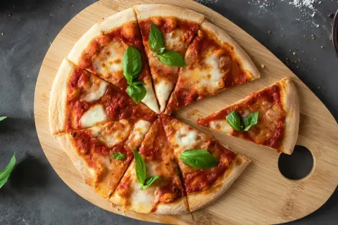 Margherita pizza na drewnianej desce, idealna na szybki przepis na ciasto do pizzy. Świeża bazylia dodaje aromatu.