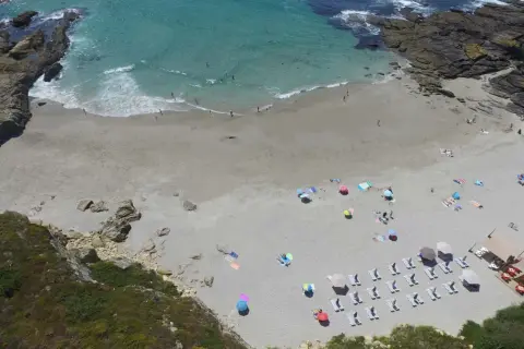Vista aérea de la playa Paxariñas con gente disfrutando del sol y el mar.