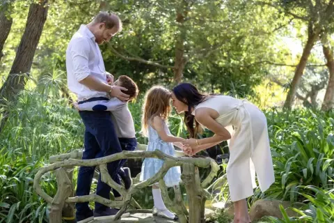 Harry y Meghan disfrutan un momento tierno con sus hijos en un puente de jardín.