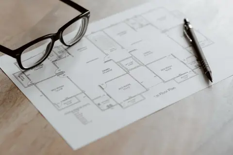Occhiali e penna su una planimetria, pronti per analizzare il cambio categoria catastale di un immobile.