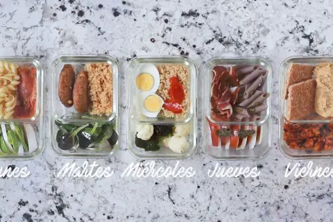 Cinco tuppers con almuerzos variados para la semana: pasta, salchichas, arroz, huevos, verduras, jamón, pan y más.