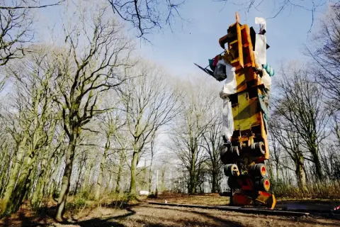 Im tony cragg skulpturenpark ragt eine bunte, auf dem Kopf stehende Konstruktion aus Metall und Stoff in den Himmel, umgeben von kahlen Bäumen.