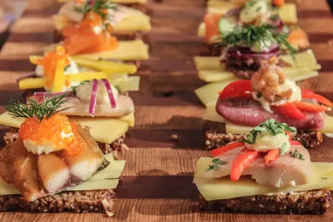 Reihe von appetitlichen Smørrebrød mit Fisch, Kaviar und Gemüse – perfektes schnelles Fingerfood für jeden Anlass.