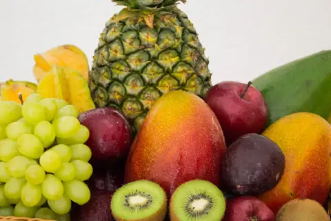 Koszyk pełen owoców: ananas, mango, winogrona, jabłka, śliwki, kiwi, awokado i karambola. Naturalna fruktoza w najlepszym wydaniu.