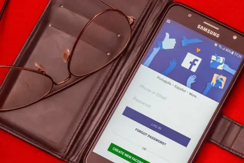 Okulary na etui, telefon z ekranem logowania Facebook. Chcesz wiedzieć, jak zmienić numer tel na FB?