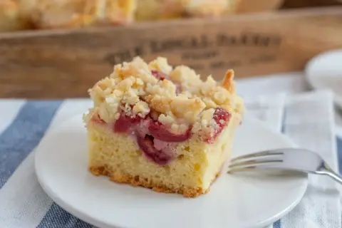 Ein Stück Kirsch-Streuselkuchen auf einem Teller, bereit zum Genießen. Dieses Streuselkuchen Rezept ist ein Klassiker.