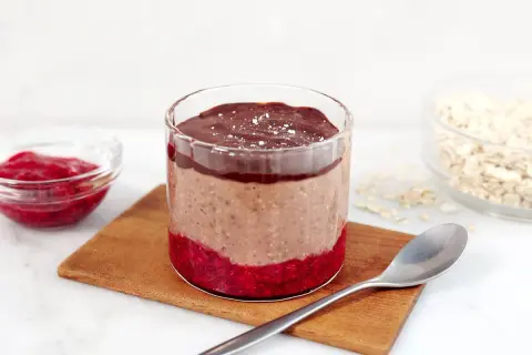 Choklad overnight oats med hallon och en sked redo att avnjutas.