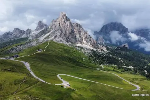 Kręta droga na Passo Giau w Dolomitach, otoczona zielonymi wzgórzami i skalistymi szczytami.