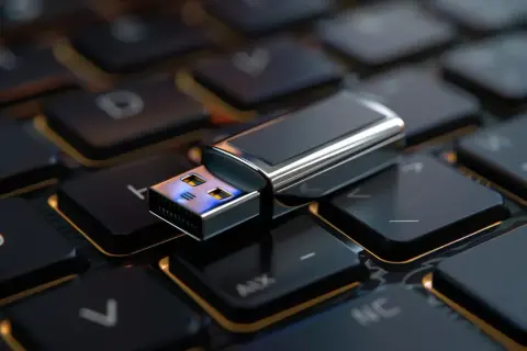 Pendrive leżący na klawiaturze komputera.