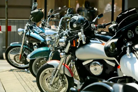 Kilka motocykli zaparkowanych na chodniku, w tym niebieski, zielony i srebrny.